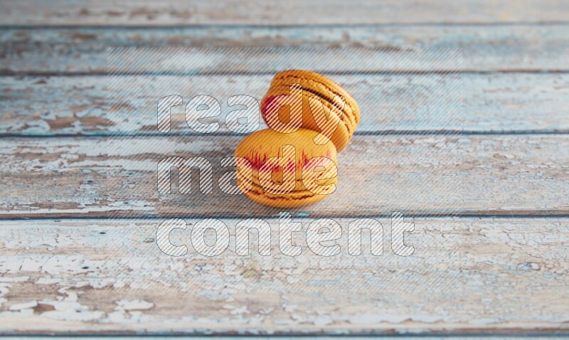 45º Shot of two orange Exotic macarons on light blue wooden background