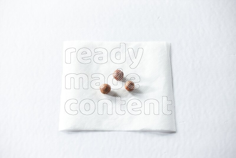 3 peeled hazelnuts on a piece of paper on a white background in different angles