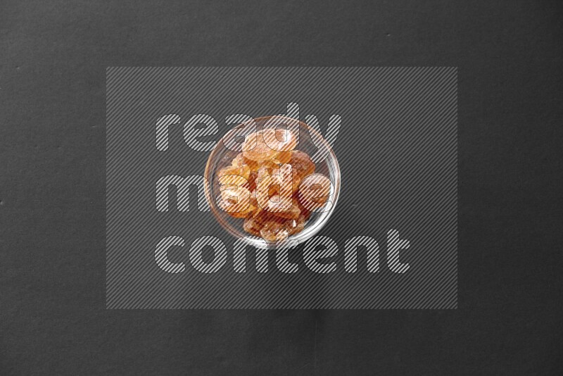 A glass bowl full of gum arabic on black flooring