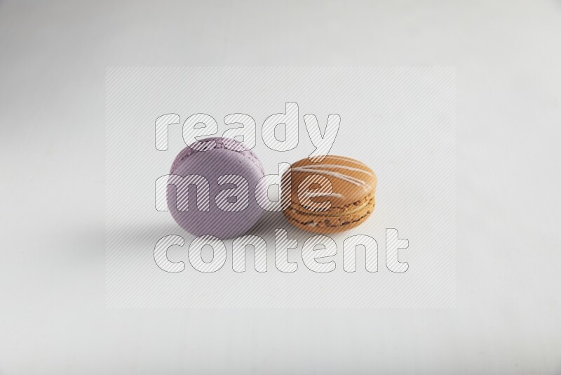 45º Shot of of two assorted Brown Irish Cream, and Purple Blueberry macarons on white background