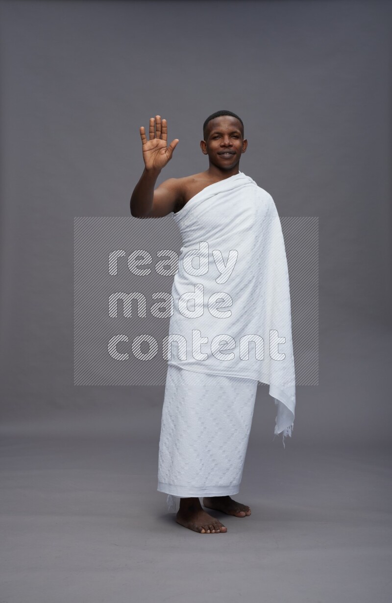 A man wearing Ehram Standing Interacting with the camera on gray background