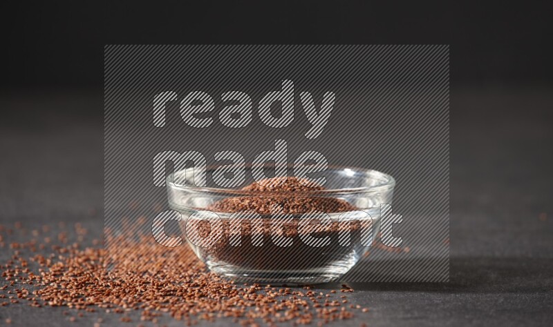 وعاء زجاجي ممتلئ ببذور حب الرشاد محاط بالبذور على أرضية سوداء