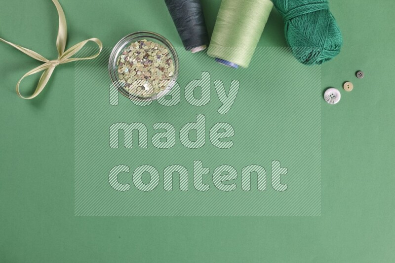 A green collection of sewing and tailoring tools arranged on a green background