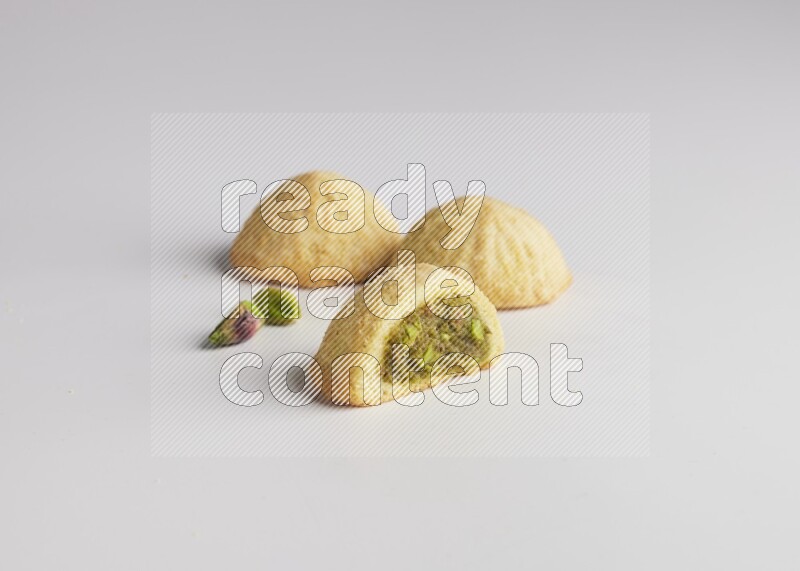 Three Pieces of Maamoul filled with pistachio paste  one of them is cut direct on white background