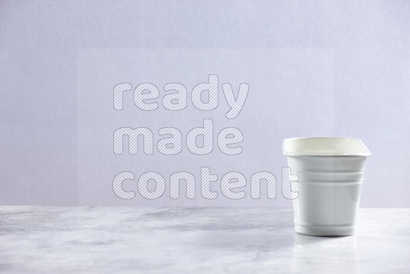 An empty white plant pot on grey marble background