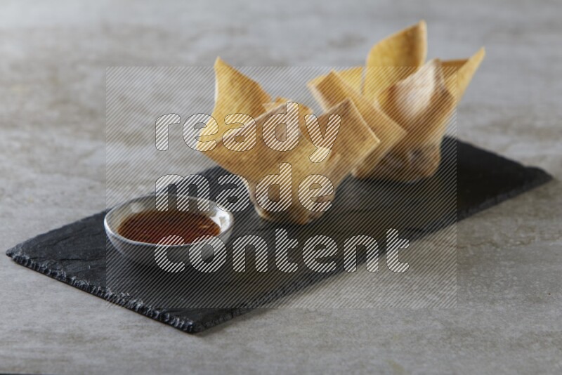 wonton cups with soy sauce ramkin on rectangle slate on grey textured counter top