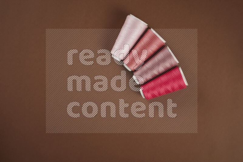 A pink collection of sewing and tailoring tools arranged on a brown background