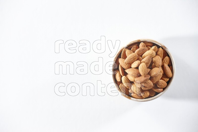 A beige ceramic bowl full of peeled almonds on a white background in different angles