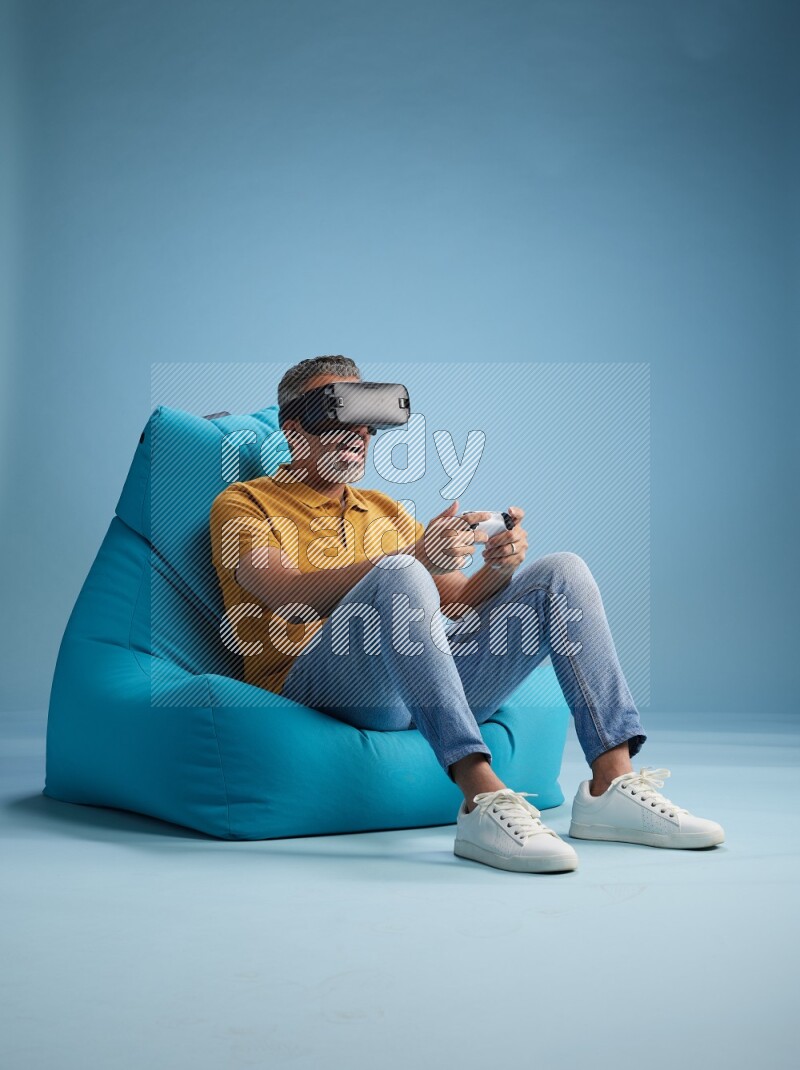 A man sitting on a blue beanbag and gaming with VR