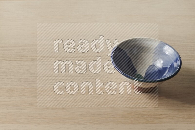A multicolored pottery bowl on light wooden background