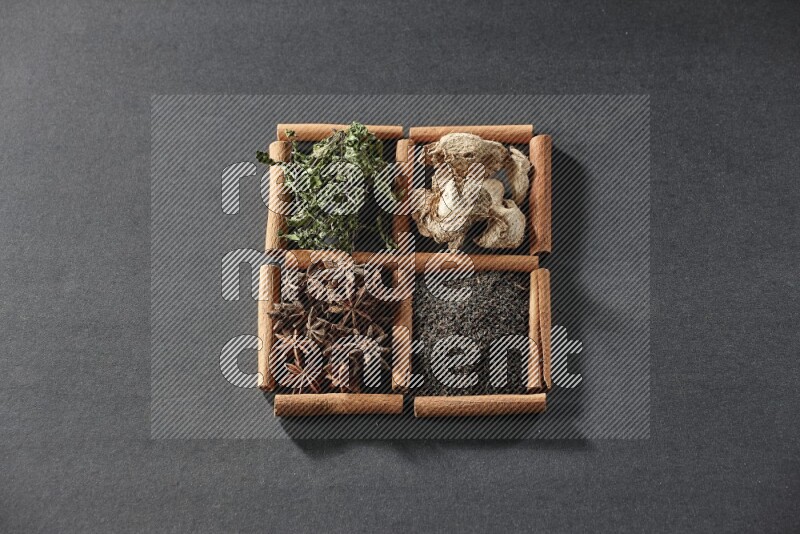 4 squares of cinnamon sticks full of black tea, dried ginger, dried mint leaves and star anise on black flooring