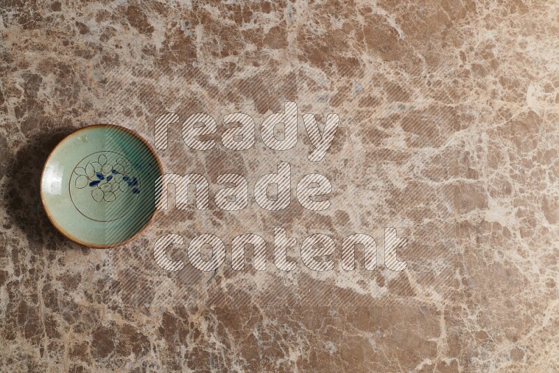 A decorative pottery plate on beige marble background