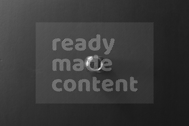 A glass spice jar full of black seeds on black flooring