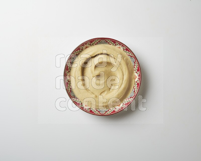 Plain Hummus in a red plate with patterns on a white background