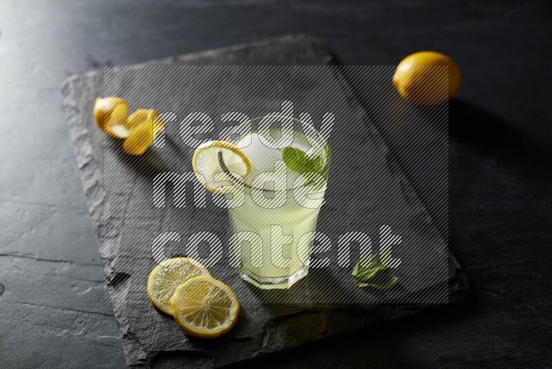 A glass of lemon juice with a lemon slice on black background