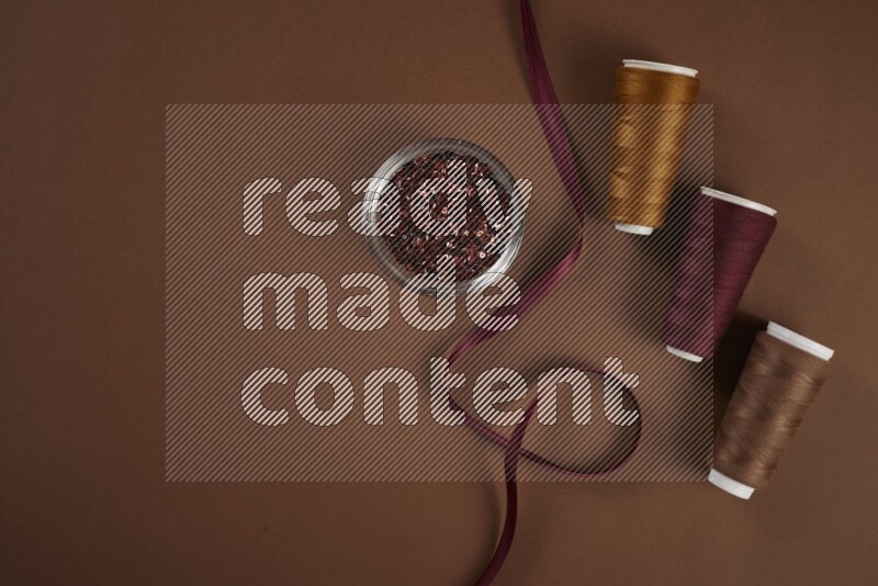 A red collection of sewing and tailoring tools arranged on a brown background