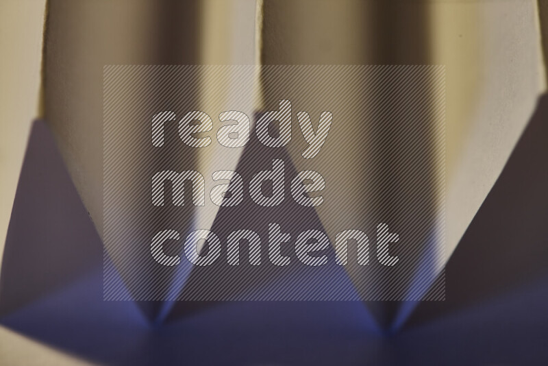 صورة مجردة مقربة تظهر طيات ورقية هندسية حادة بتدرجات اللون الأزرق مع درجات لونية دافئة