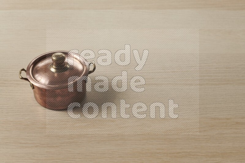 A small copper pot on light wooden background
