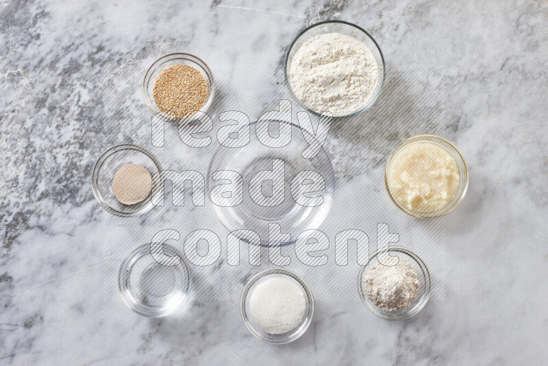 Kahk step by step with its ingredients ghee, sugar, flour, sesame, yeast, water and kahk flavor on grey marble background
