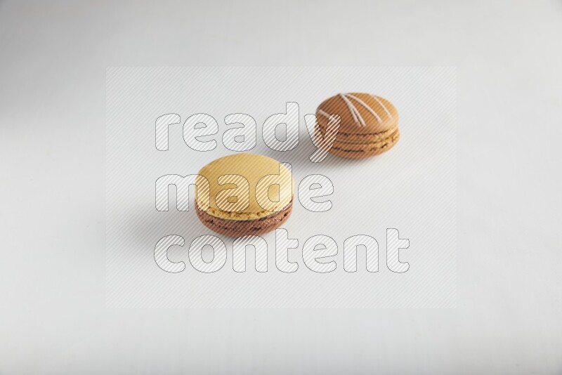 45º Shot of of two assorted Brown Irish Cream, and Yellow, and Brown Chai Latte macarons on white background