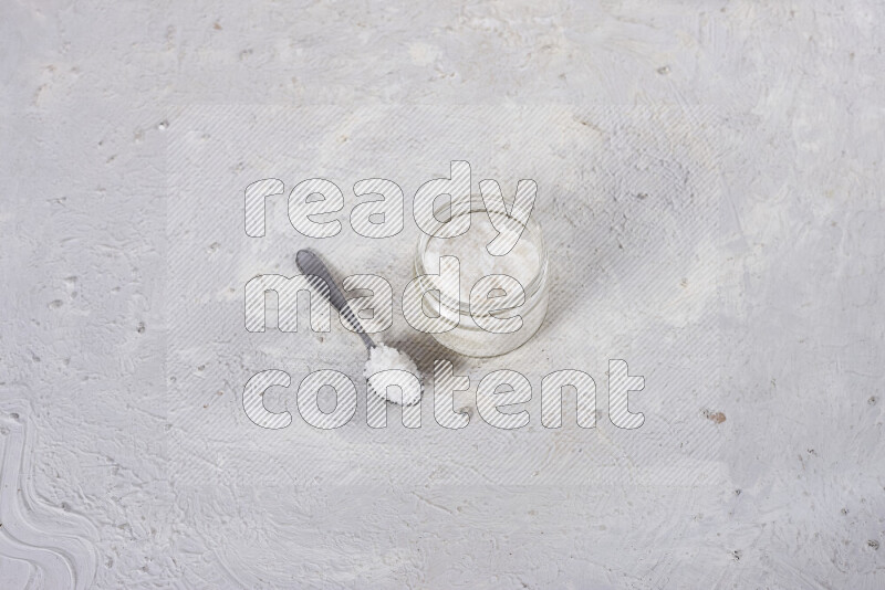 A glass jar full of coarse sea salt crystals on white background