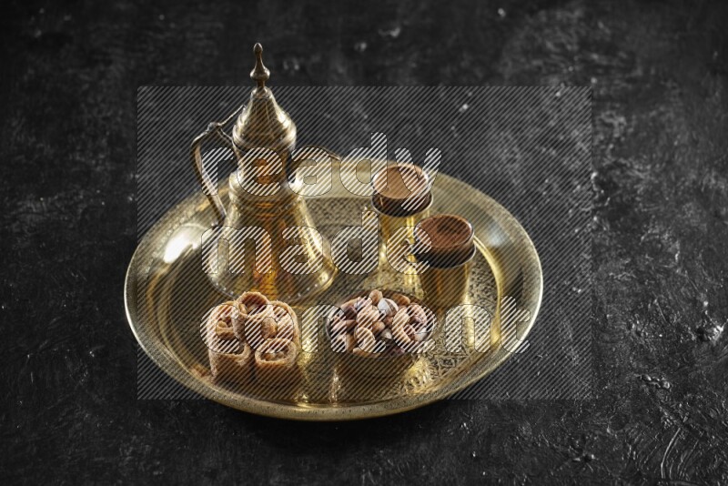 Oriental sweets with nuts and a drink on a metal tray in a dark setup