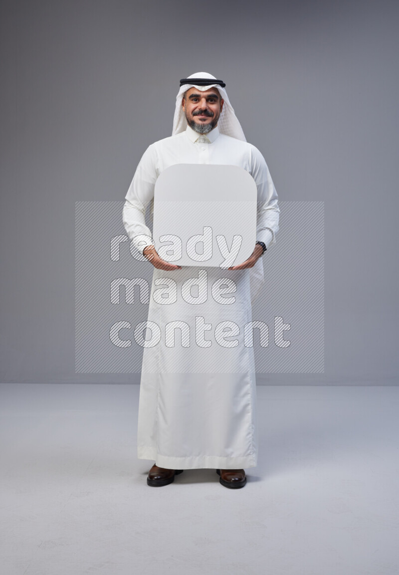 Saudi man Wearing Thob and white Shomag standing holding social media sign on Gray background