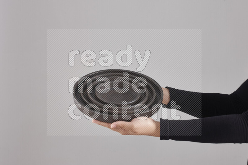 A woman in black abaya holding different pottery essentials in different positions