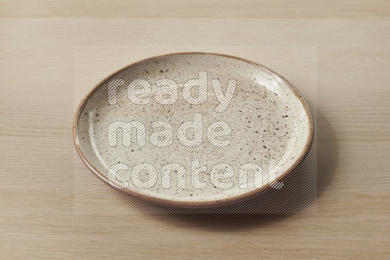 A beige pottery plate on light wooden background