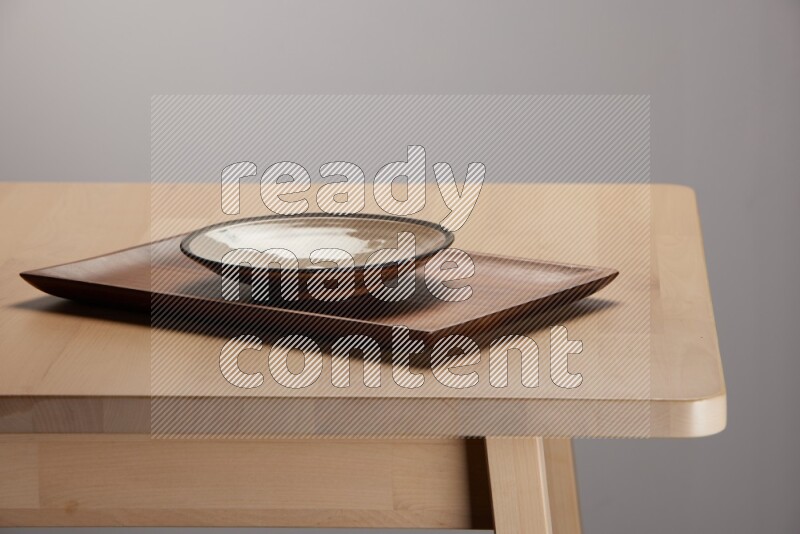 multicolored plate on a rectangular wooden tray on the edge of wooden table