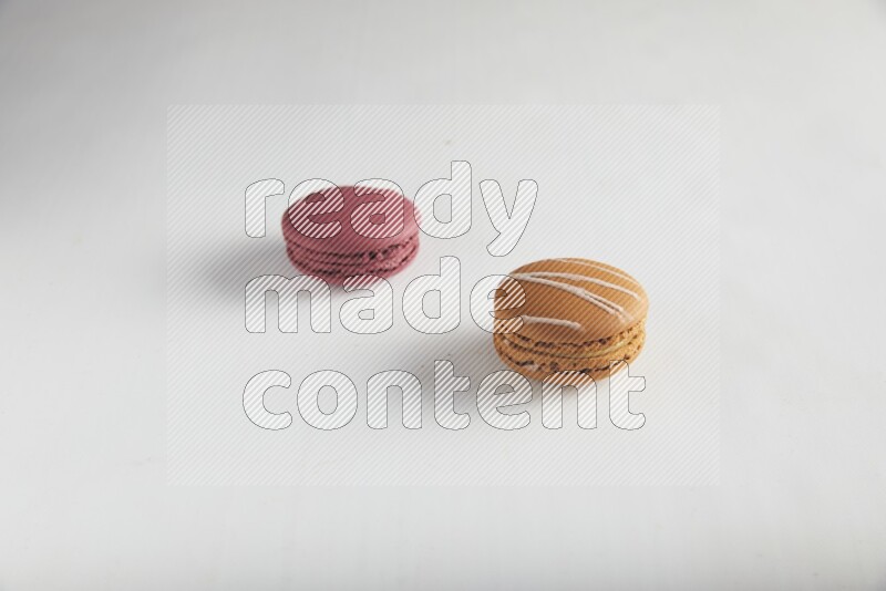 45º Shot of of two assorted Brown Irish Cream, and Red Cherry macarons on white background