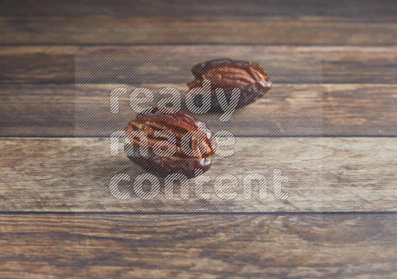 two pecan stuffed madjoul date on a wooden background