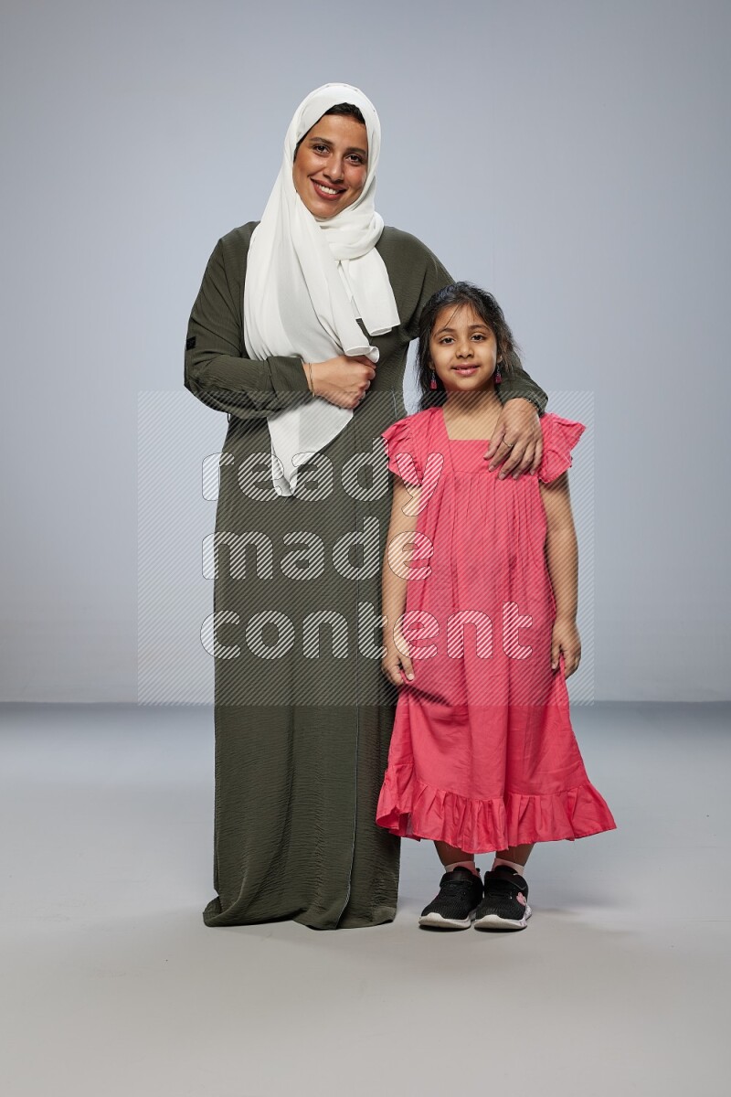A girl and her mother interacting with the camera on gray background