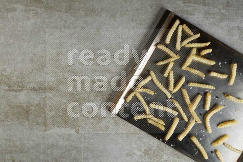 crinkle fries in a black stainless steel rectangle tray on grey textured counter top