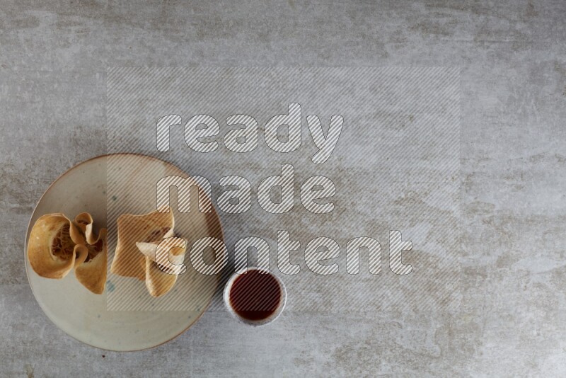 wonton cups with soy sauce ramkin on multi colored pottery on grey textured counter top