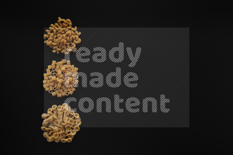 Different pasta types in 3 bunches on black background