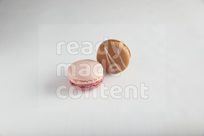 45º Shot of of two assorted Brown Irish Cream, and Pink Litchi Raspberry macarons on white background