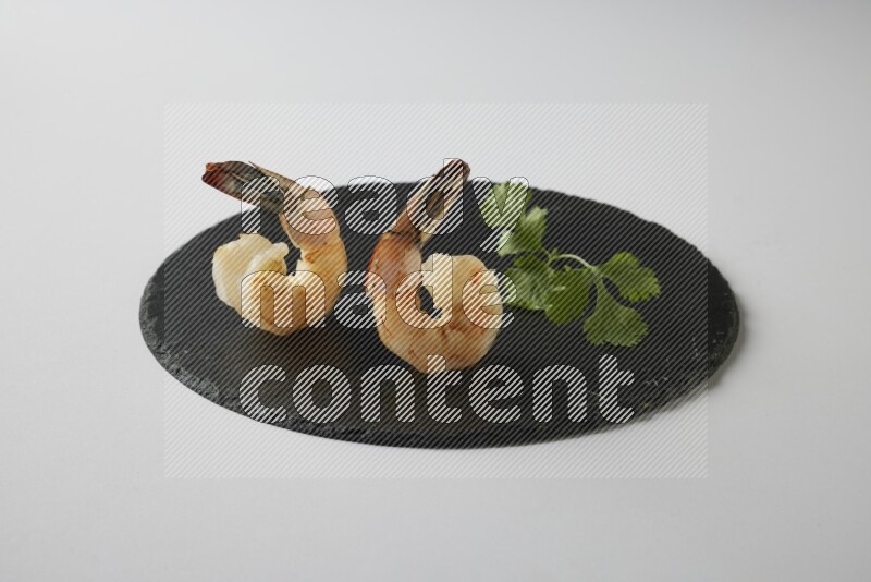 two grilled shrimp  on a black slate direct  on a white back ground