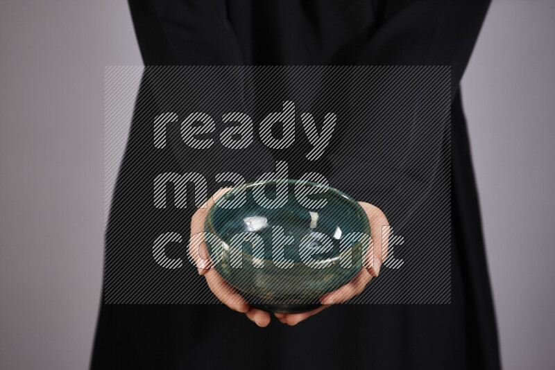A woman in black abaya holding different pottery essentials in different positions