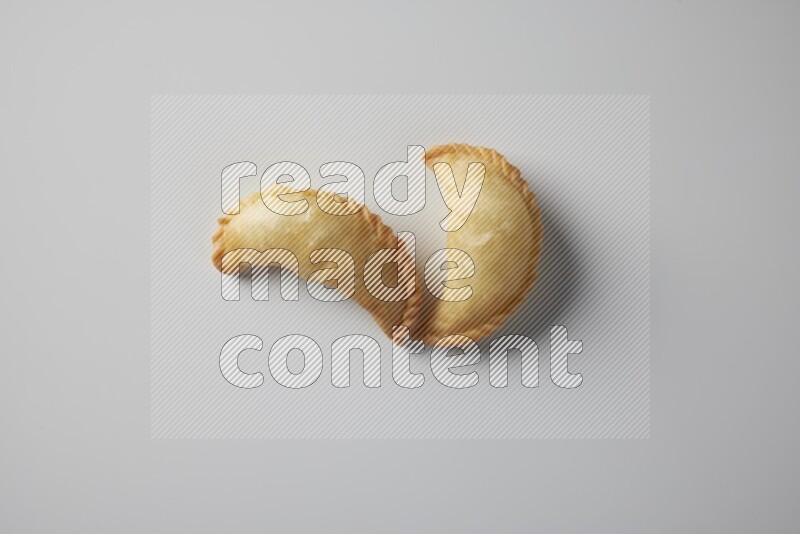 Two fried sambosa from a top angle on a white background