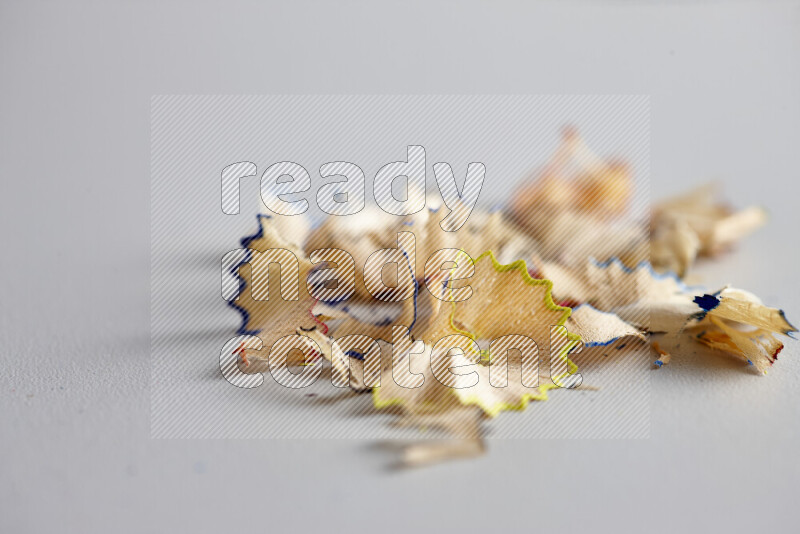 صورة مقربة تظهر كومة صغيرة من نشارة الأقلام ذات حواف ملونة متنوعة علي خلفية رمادية