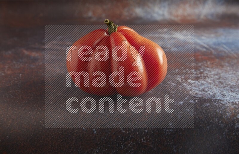 45 degree single heirloom tomato on  a textured reddish rustic metal background