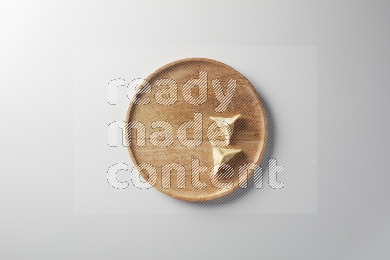 Two Sambosas on a wooden round plate on a white background