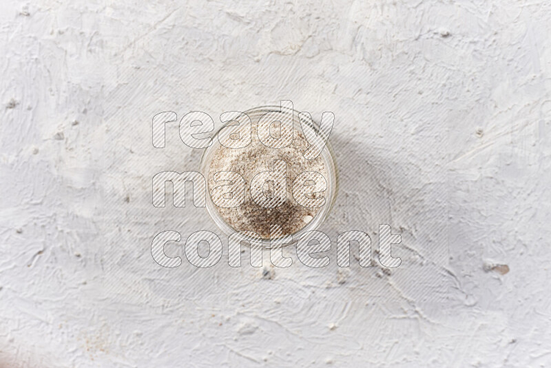A glass jar full of onion powder on white background
