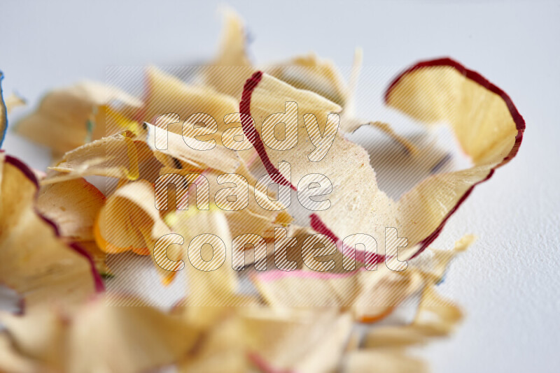 A close-up showing a small pile of pencil shavings with varied color edges on grey background