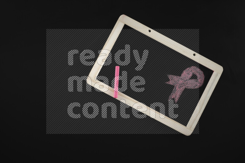 A drawing of pink ribbon on blackboard on black background