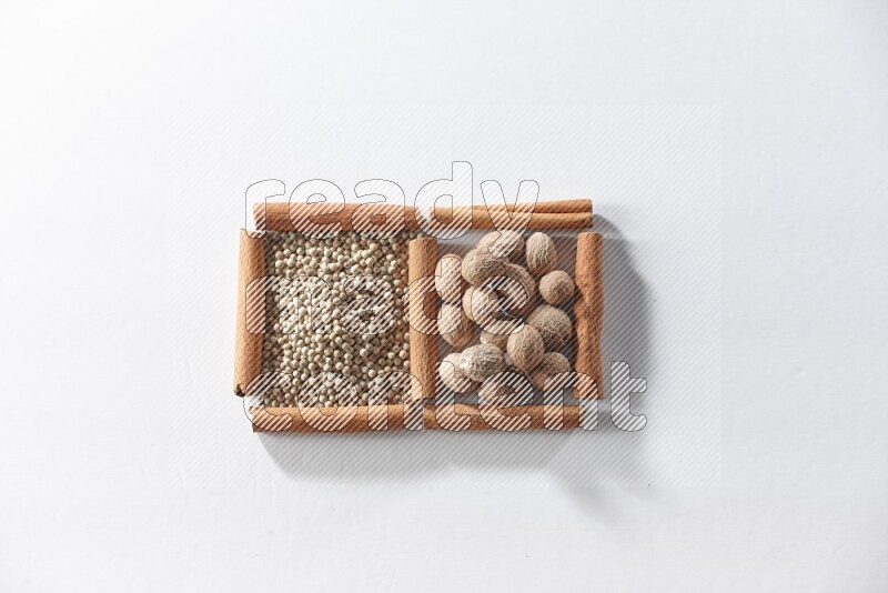 2 squares of cinnamon sticks full of white pepper and nutmegs on white flooring