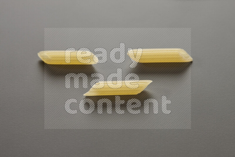 Mini penne pasta on grey background