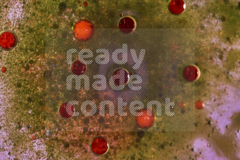 لقطات مقربة لقطرات ألوان مائية خضراء وحمراء على سطح الزيت على خلفية وردية