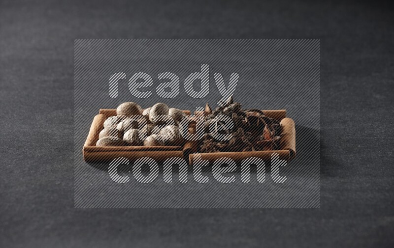 2 squares of cinnamon sticks full of nutmeg and star anise on black flooring